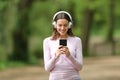 Happy woman walking listening to music on phone in a park Royalty Free Stock Photo