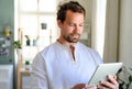 Front view portrait of man using tablet at home.