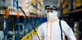 Man worker with protective mask and suit disinfecting industrial factory with spray gun.