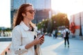 Front view portrait modern fashion happy woman hipster walking and using a smart phone on a city street wearing Royalty Free Stock Photo