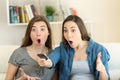 Two amazed friends watching tv at home Royalty Free Stock Photo