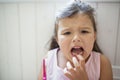 Front view portrait of worried small girl indoors, loosing baby tooth.