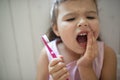 Front view portrait of worried small girl indoors, loosing baby tooth.