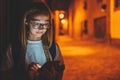 Front view portrait of young girl tourist with reflection of glare in glasses from mobile phone screen uses Internet technology