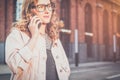 Front view.Portrait of young woman in glasses standing outdoors and talking on cell phone. Royalty Free Stock Photo