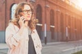 Front view.Portrait of young woman in glasses standing outdoors and talking on cell phone.