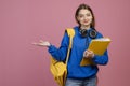 Pretty brunette schoolgirl standing, holding yellow backpack and folder. Royalty Free Stock Photo