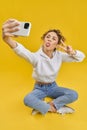 Girl sitting in lotos pose, taking selfie.