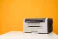 Front view of a printer and a blank sheet of a4 paper on a white table on a yellow background Royalty Free Stock Photo
