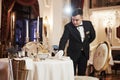 Front view. Process of preparing place for special visitors. Waiter in classical wear works on the servering Royalty Free Stock Photo