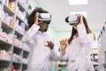 Front view of professional multiethnic team of African and Caucasian women pharmacists, working with virtual reality