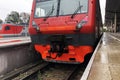 Front view of red train standing on platform on railway station ready for departure. Royalty Free Stock Photo