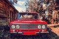 Front view of a red vintage Lada car in the countryside. Old wooden barn from the side. Old red Soviet car Royalty Free Stock Photo