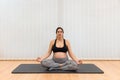 A relaxed pregnant woman sitting on a mat doing yoga at home with copy space