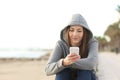 Front view of a relaxed teen uses a smart phone on the beach