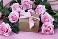 Front view of rose flowers and giftbox on a pink background for Mothers Day or Valentines holiday concept