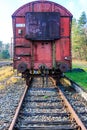 Front view of a rusty red metal freight car on disused train tracks at old station Royalty Free Stock Photo