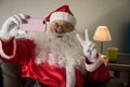 Front view of Santa Claus sitting in sofa at home Using cell phone for communication and leisure. Taking a photograph