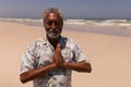 Senior black man with hands clasped praying on beach Royalty Free Stock Photo
