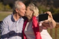 Senior couple taking selfie with mobile phone while kissing each other