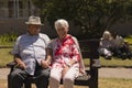 Front view of senior couple holding hands and sitting on bench in garden Royalty Free Stock Photo