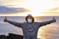 Front view of senior man with hood on head standing on top of cliff with ocean behind him. One people enjoying a winter day at sea Royalty Free Stock Photo