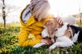 Front view of senior woman lying on grass in spring, petting pet dog.