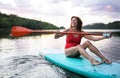 Senior woman paddleboarding on lake in summer. Copy space.