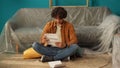 Front view shot of apartment living room. Man sitting on the floor in the room holding eviction documents, shocked upset