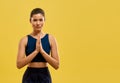 Slim woman holding prayer hands, looking at camera.