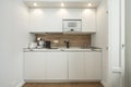 Front view of small kitchen in white and oak wood tones, microwave and accessories included Royalty Free Stock Photo