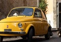 Front view of small vintage and antique yellow car in european old city streets Royalty Free Stock Photo