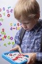 Front view of smart boy holding abacus against green chalkboard in a classroom at elementary school Royalty Free Stock Photo