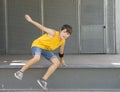 Front view of smiling boy jumping over a metallic fence while looking camera on a bright day Royalty Free Stock Photo