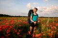Front view of smiling female tourist who stands on field of red poppies. Royalty Free Stock Photo