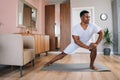 Front view of smiling strong African-American man doing side lunge exercise at home