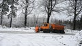 View of snowplow service truck - gritter car spreading salt on the road. Maintenance of roads in winter in the mountains