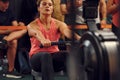 Front view. Sportive woman doing exercises on rowing machine in the gym