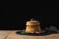 Front view of Stack of homemade plain pancakes with strawberries, blueberries and maple syrup served on black plate on
