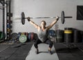 Front view of strong young woman lifting weights over her head Royalty Free Stock Photo