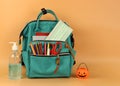 Student backpack , medical mask , alcohol gel and halloween pumpkin bucket on orange background with copy space. Education ,