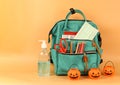 Student backpack , medical mask , alcohol gel and halloween pumpkin bucket on orange background with copy space. Education ,