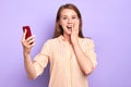 Suprised funny young woman smiling broadly, holding red cell phone Royalty Free Stock Photo