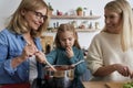 Front view of three generations women cooking in the kitchen