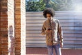 Front view of a cool young smiling afro man using a mobile phone while standing outdoors in a sunny day Royalty Free Stock Photo