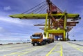 Front view of truck fleet line up under quay crane leaving the port after discharging containers with sea and blue sky background.