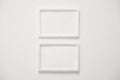 front view of two blank white horizontal photo frames hanging on clean white cement wall, interior design background concept Royalty Free Stock Photo