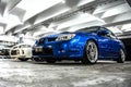 Front view of two blue Subaru Impreza and white Mitsubishi Lancer Evo 4