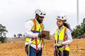 Front view of two engineers african american man and woman in uniform discuss and use tablet working with wind turbine model Royalty Free Stock Photo