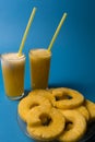 Two glasses of pineapple fruit juice and pineapple fruit over blue background Royalty Free Stock Photo